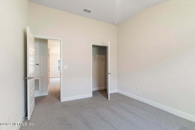 unfurnished bedroom with light colored carpet and a closet