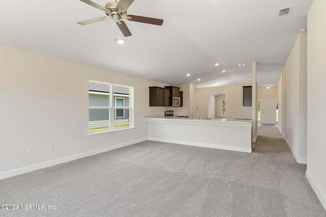 unfurnished living room featuring lofted ceiling, ceiling fan, light colored carpet, and sink