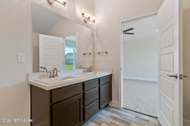 full bath with double vanity, baseboards, a sink, and wood finished floors