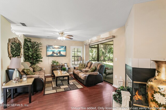 living room with ceiling fan, a tiled fireplace, and dark hardwood / wood-style flooring