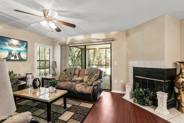 living room with ceiling fan, a textured ceiling, a fireplace, and hardwood / wood-style floors