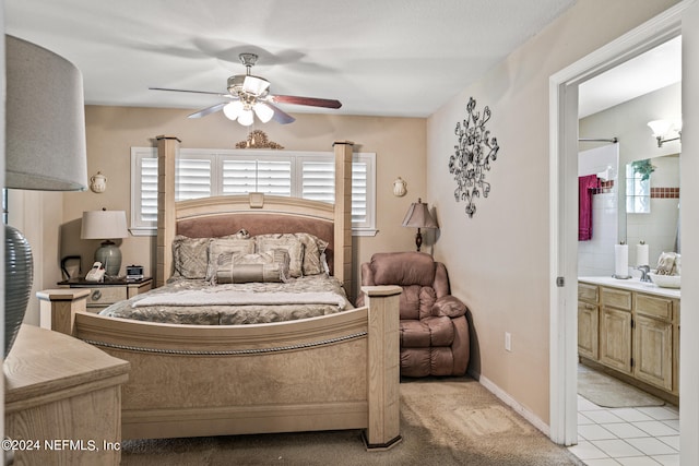 bedroom with light colored carpet, connected bathroom, sink, and ceiling fan