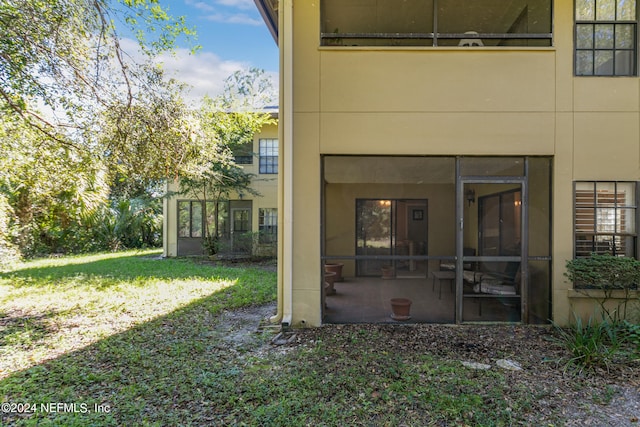 rear view of property featuring a yard and a sunroom