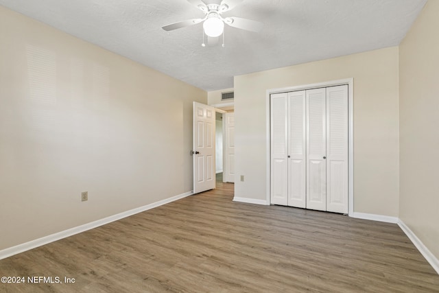 unfurnished bedroom with hardwood / wood-style flooring, ceiling fan, and a closet