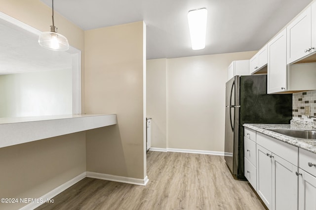 kitchen with pendant lighting, backsplash, sink, light stone counters, and white cabinetry