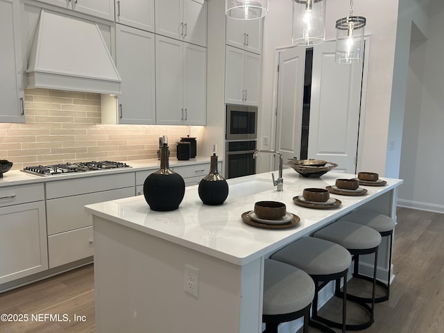 49 Pathway Ct, Saint Johns, FL 32259 - kitchen featuring appliances with stainless steel finishes, custom range hood, a breakfast bar, wood finished floors, and backsplash