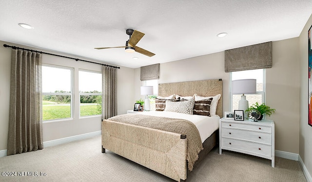 bedroom featuring ceiling fan, light colored carpet, and a textured ceiling