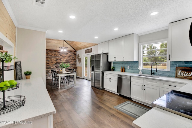 kitchen with white cabinets, sink, decorative light fixtures, dark wood-type flooring, and stainless steel appliances