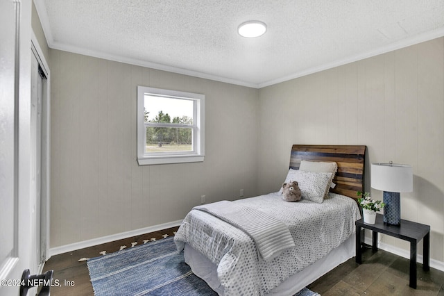 bedroom with a textured ceiling, crown molding, and dark wood-type flooring