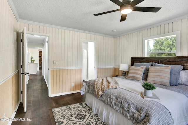 bedroom with a textured ceiling, dark wood-type flooring, wood walls, crown molding, and ceiling fan