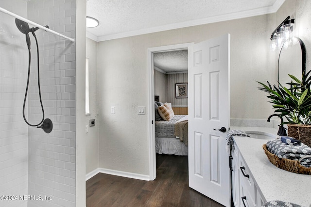 bathroom featuring tiled shower, vanity, a textured ceiling, crown molding, and hardwood / wood-style flooring