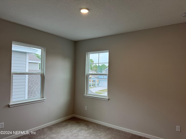 carpeted empty room with a textured ceiling