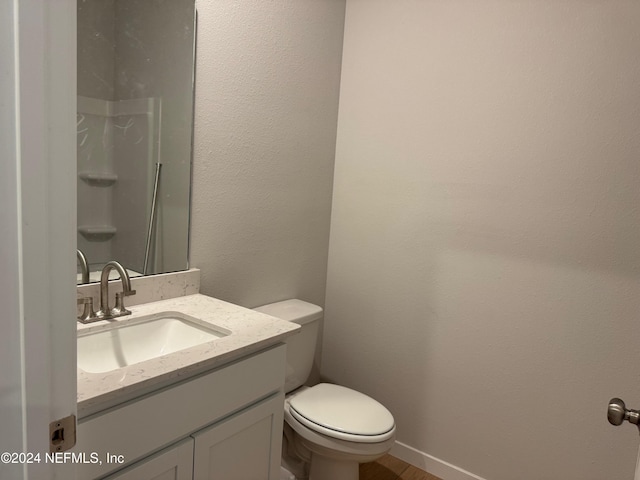 bathroom featuring walk in shower, vanity, and toilet