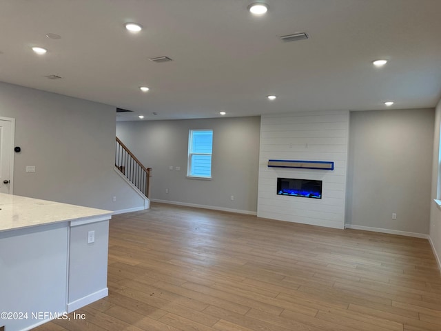 unfurnished living room featuring a large fireplace and light wood-type flooring