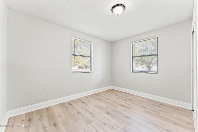 spare room with baseboards and light wood finished floors