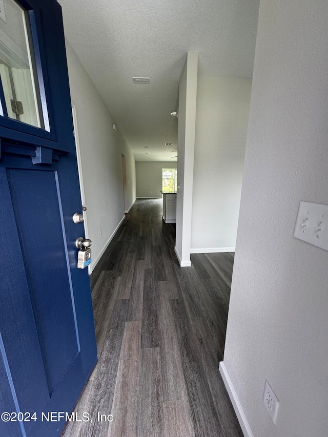 hallway with a textured ceiling and dark wood-type flooring