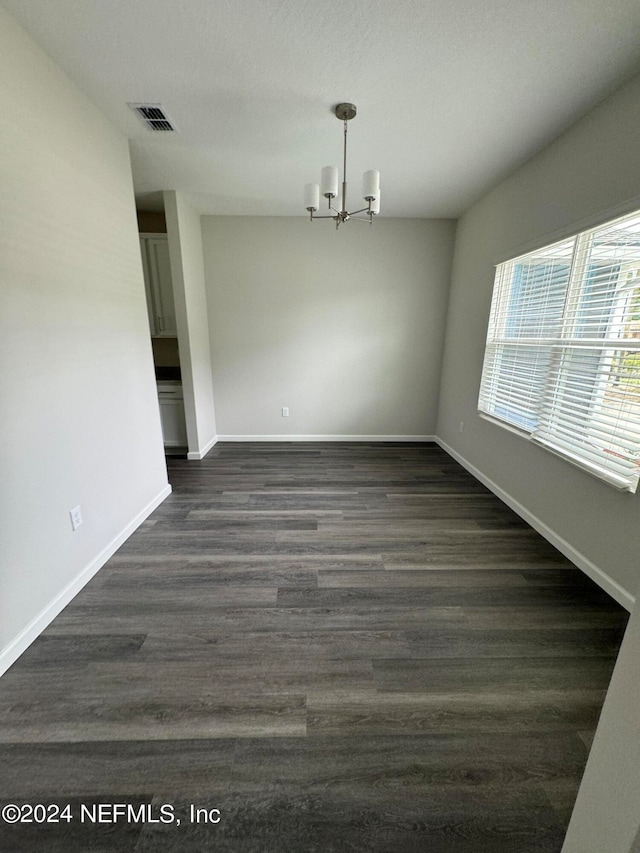 unfurnished dining area featuring dark hardwood / wood-style flooring and a chandelier