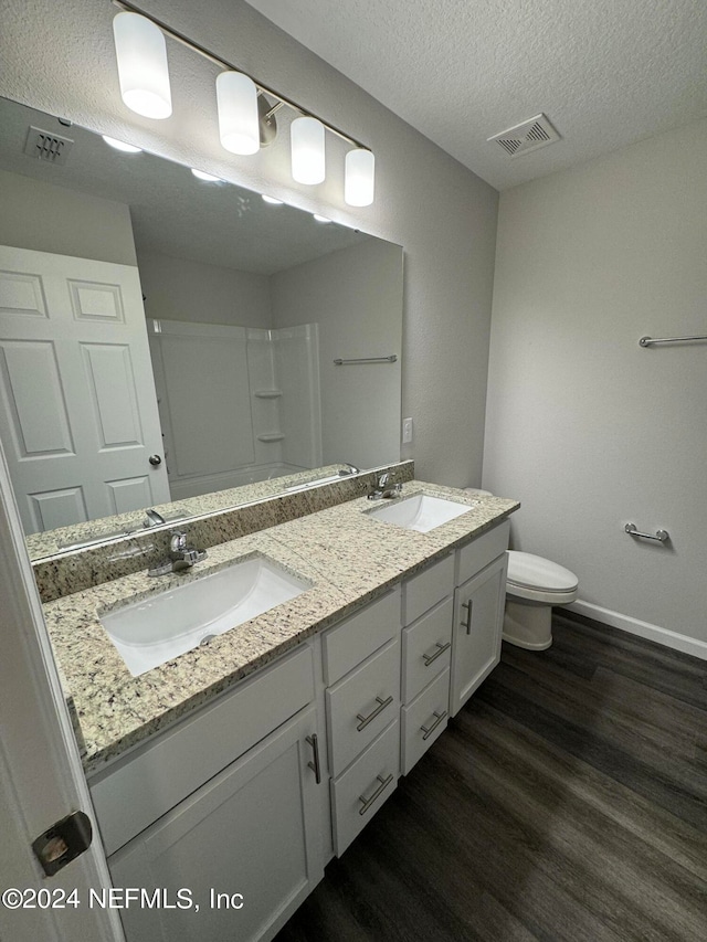 bathroom with a textured ceiling, hardwood / wood-style floors, vanity, and toilet