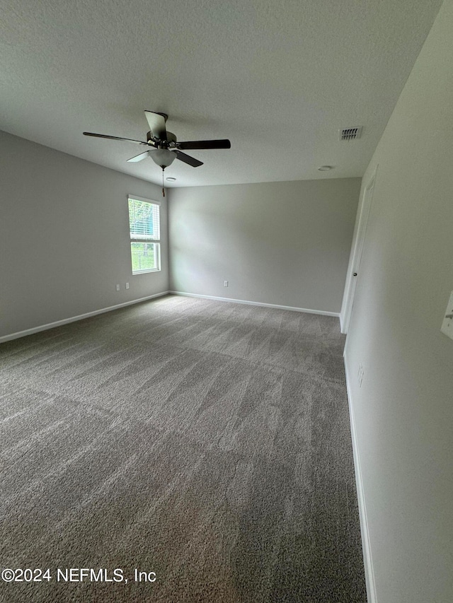 spare room with a textured ceiling, carpet flooring, and ceiling fan