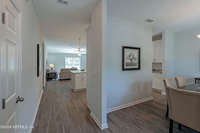 hallway with a textured ceiling and dark hardwood / wood-style floors