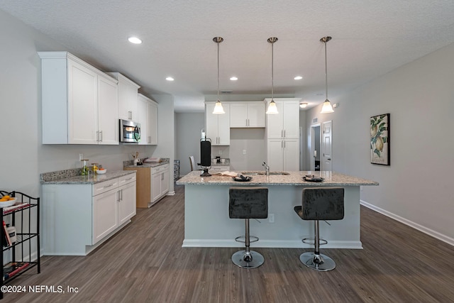 kitchen with a center island with sink, dark hardwood / wood-style flooring, and white cabinetry