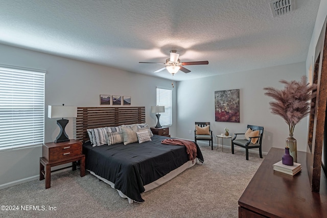 carpeted bedroom with ceiling fan and a textured ceiling