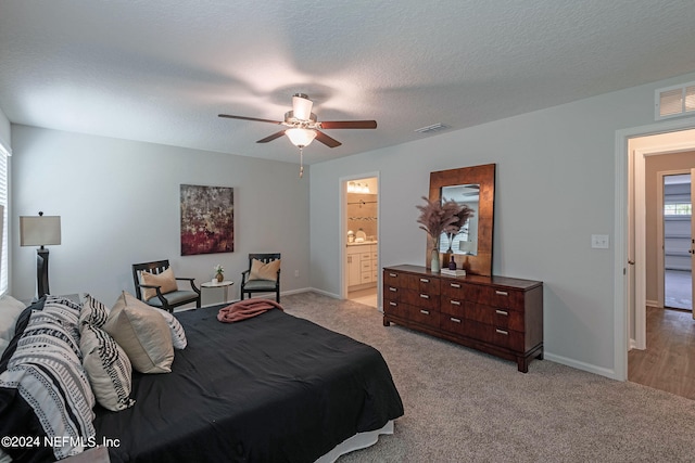 bedroom featuring ceiling fan, light colored carpet, a textured ceiling, and connected bathroom