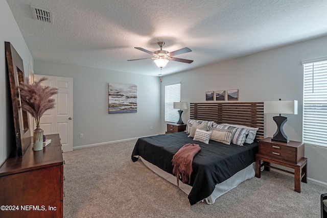 carpeted bedroom featuring a textured ceiling and ceiling fan