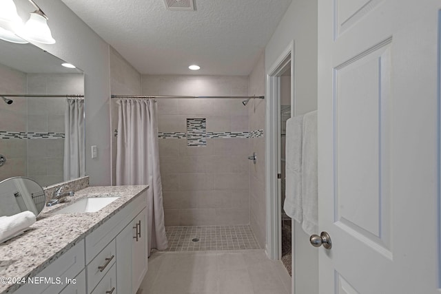 bathroom featuring a textured ceiling, tile patterned flooring, vanity, and curtained shower