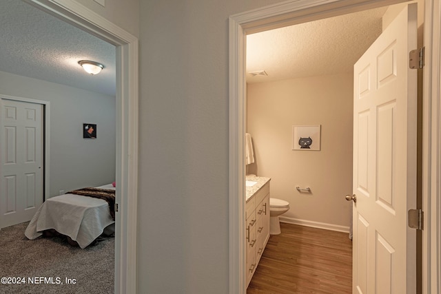 bathroom featuring vanity, toilet, a textured ceiling, and hardwood / wood-style flooring