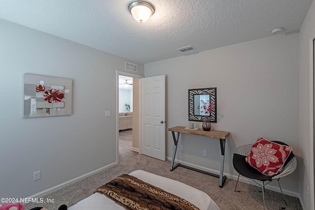 bedroom with a textured ceiling and light carpet