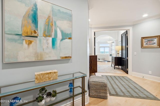 hallway with light hardwood / wood-style flooring and ornamental molding