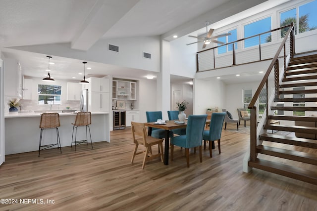 dining area featuring light hardwood / wood-style flooring, beamed ceiling, and wine cooler