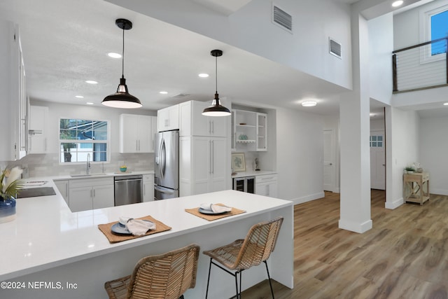 kitchen with wine cooler, appliances with stainless steel finishes, white cabinets, a breakfast bar area, and kitchen peninsula