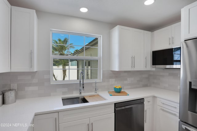 kitchen featuring white cabinetry, sink, backsplash, and appliances with stainless steel finishes