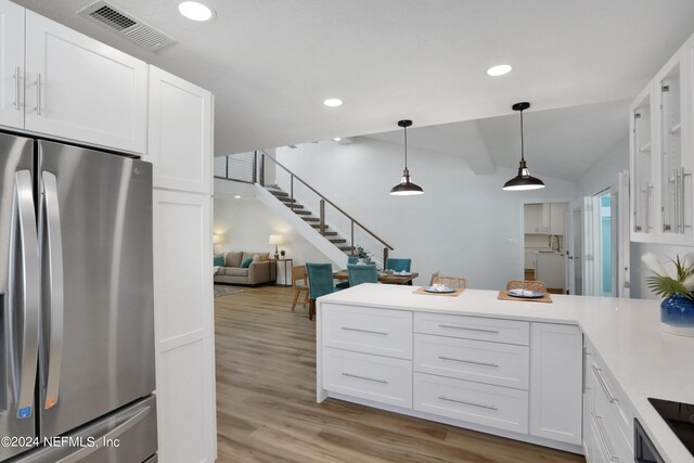 kitchen featuring white cabinets, stainless steel fridge, light hardwood / wood-style flooring, and hanging light fixtures