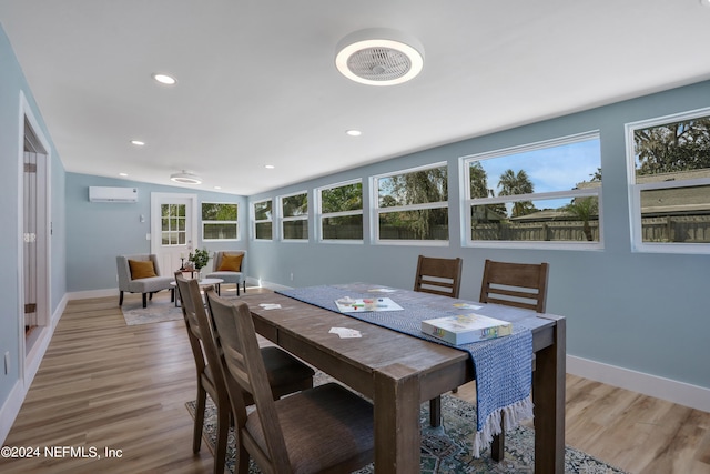 dining room with lofted ceiling, a wall mounted AC, and light hardwood / wood-style flooring