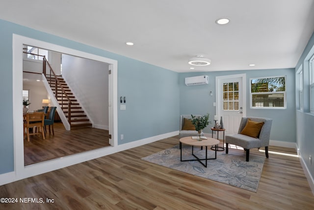 sitting room featuring an AC wall unit and hardwood / wood-style flooring