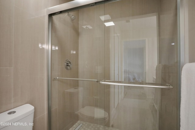 bathroom featuring tile walls, toilet, and a shower with door