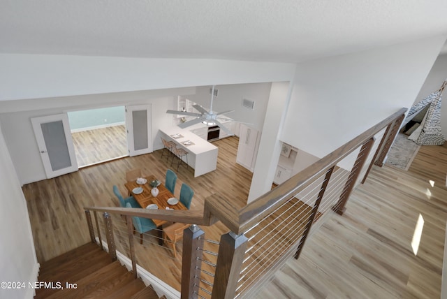 stairs featuring hardwood / wood-style floors, ceiling fan, and lofted ceiling