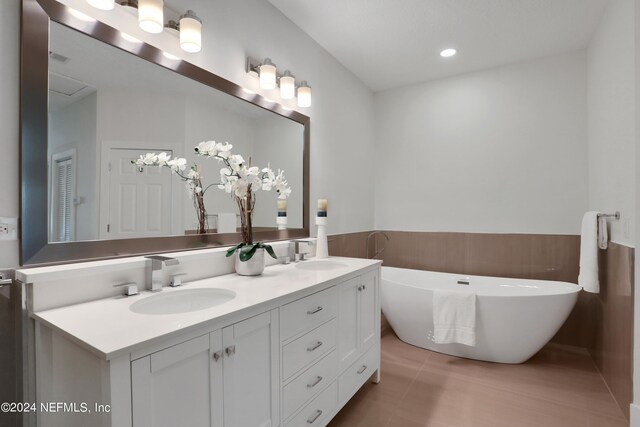 bathroom featuring a bathing tub, tile patterned flooring, and vanity