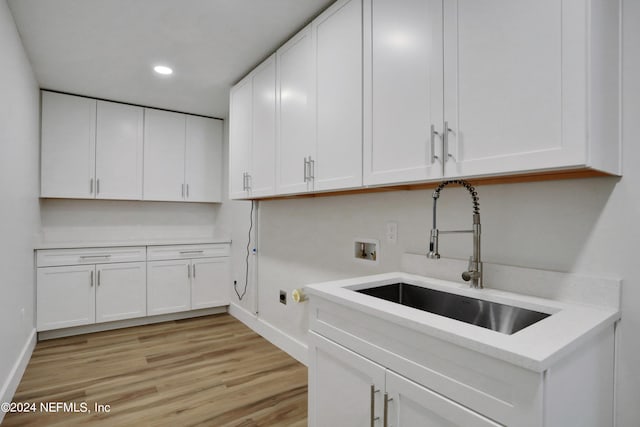 clothes washing area featuring cabinets, light wood-type flooring, hookup for a washing machine, and sink