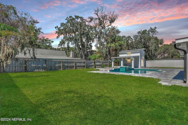 yard at dusk featuring an outbuilding, a fenced in pool, and a patio