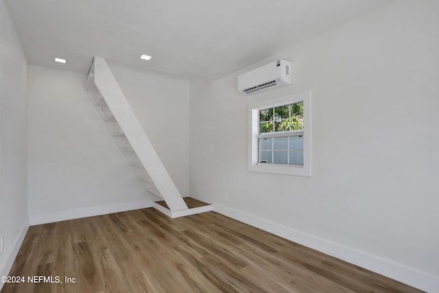 unfurnished room featuring wood-type flooring and a wall mounted AC