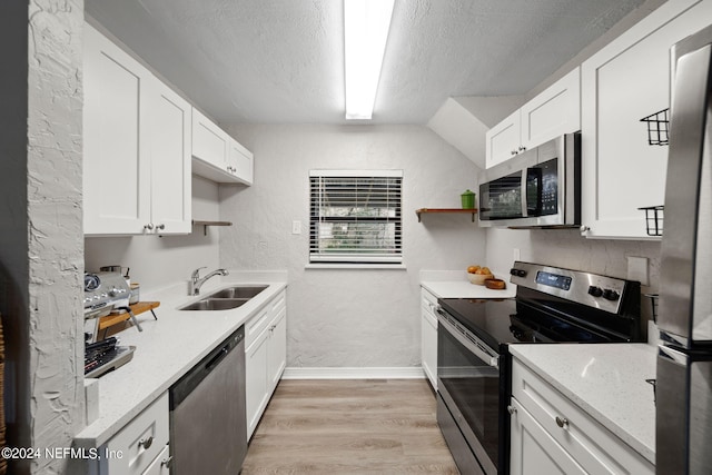 kitchen with lofted ceiling, white cabinets, sink, light hardwood / wood-style floors, and stainless steel appliances