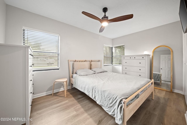 bedroom featuring ceiling fan, light hardwood / wood-style flooring, and multiple windows