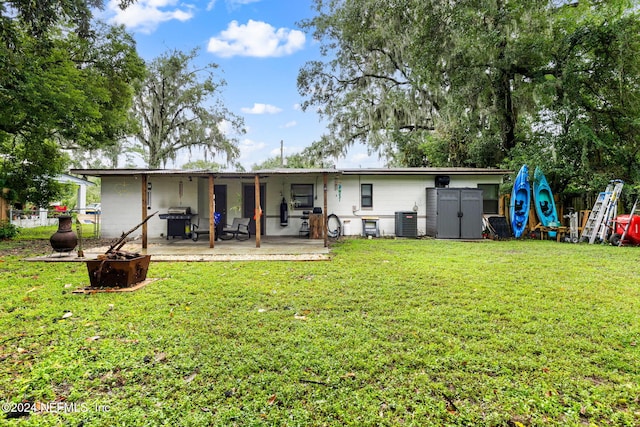 back of house with a lawn, a storage unit, central air condition unit, and a patio