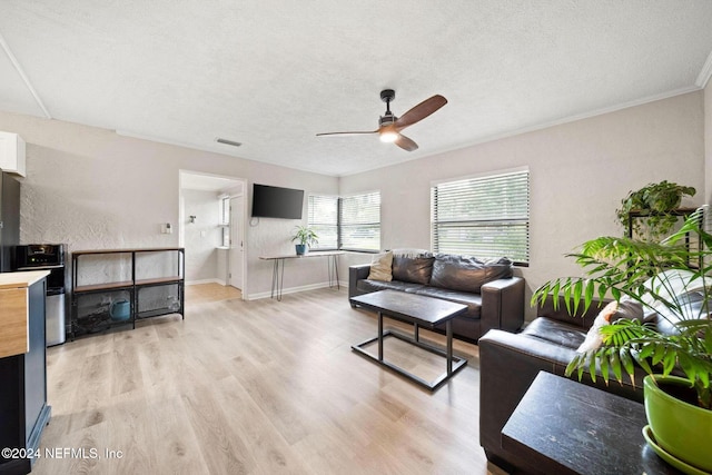 living room with ceiling fan, light hardwood / wood-style floors, a textured ceiling, and ornamental molding