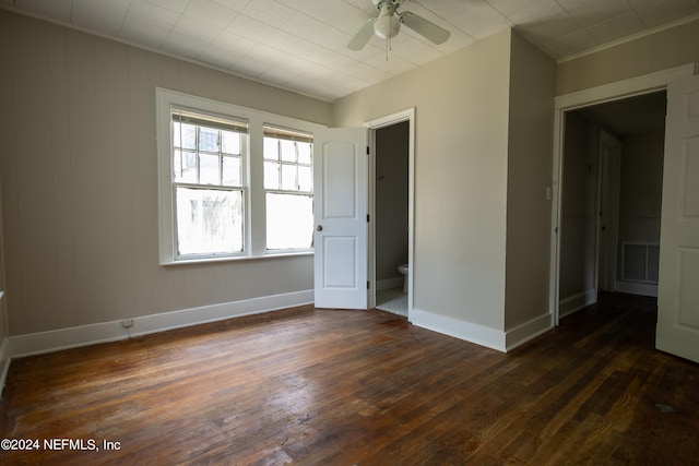 unfurnished bedroom with connected bathroom, dark hardwood / wood-style floors, and multiple windows