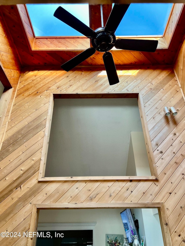 details with wooden walls, ceiling fan, and a skylight